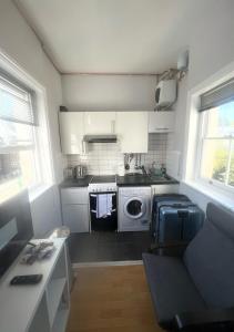 uma pequena cozinha com armários brancos e um fogão em Quirky Studio Camden em Londres