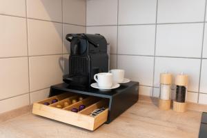 a black coffee maker with cups and a box of wine at Blumenhaller Boardinghouse in Osnabrück