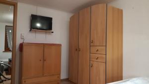 1 dormitorio con armarios de madera y TV en la pared en " Haus Willi " Sohlbach, en Netphen