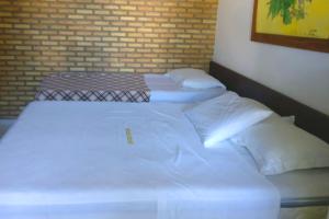 two beds with white sheets and pillows in a room at Pousada Grauça in Cacha Pregos