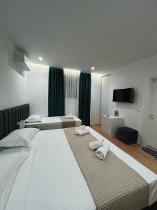 1 dormitorio con 2 camas grandes y toallas. en Clinton Tirana Inn, en Tirana