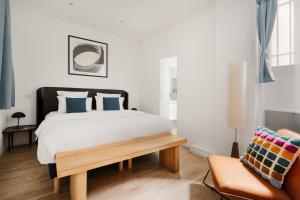 a bedroom with a large bed and a chair at Edgar Suites Marais - Réaumur in Paris