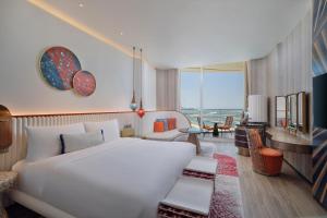 a bedroom with a large white bed and a living room at W Dubai - Mina Seyahi, Adults Only in Dubai