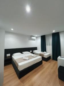 ティラナにあるClinton Tirana Innのベッド2台とテレビが備わるホテルルームです。