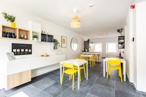 a kitchen and dining room with yellow chairs and tables at Le Gîtel in Spa