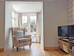 un salon avec une chaise et une télévision dans l'établissement Spence Cottage, Birdham, à Birdham