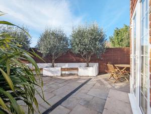a patio with two trees and a table and chairs at Spence Cottage, Birdham in Birdham