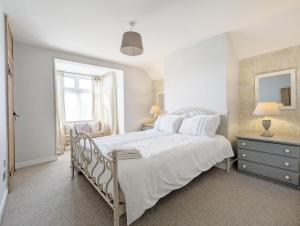 a white bedroom with a white bed and a window at Spence Cottage, Birdham in Birdham