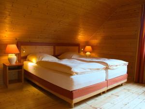 ハッセルフェルデにあるHoliday Home Auerhahn-1 by Interhomeのランプ2つ付きの木造の部屋のベッド1台