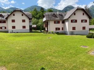 two large white buildings in a field with mountains in the background at Nice apartment with terrace and garden view in Bohinj