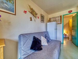 a living room with a blue couch and a refrigerator at Apartment Vostok Zodiaque-61 by Interhome in Le Corbier