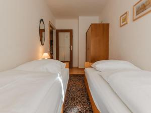 dwa łóżka w pokoju z białymi prześcieradłami w obiekcie Apartment Martini by Interhome w mieście Bad Gastein