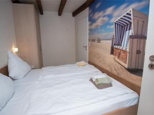 ノルトダイヒにあるHoliday Home Venusmuschel by Interhomeのベッドルーム1室(白いベッド1台、ビーチの写真付)