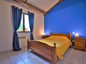 a bedroom with a yellow bed and a blue wall at Holiday Home Au Cayroux - BSB302 by Interhome in Blanquefort-sur-Briolance