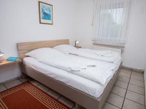 a bed with white sheets in a room with a window at Holiday Home Seefalke by Interhome in Norddeich