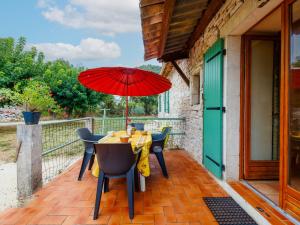 a table with a red umbrella on a patio at Holiday Home Lozard by Interhome in Barjac