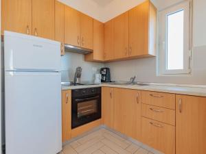 - une cuisine avec des placards en bois et un réfrigérateur blanc dans l'établissement Apartment Mlasina-3 by Interhome, à Nin