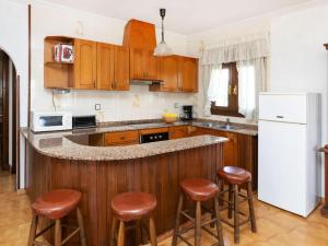 a kitchen with wooden cabinets and a counter with stools at Holiday Home Castilla by Interhome in Miami Platja