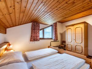 two beds in a room with a wooden ceiling at Apartment Alpenrose-3 by Interhome 