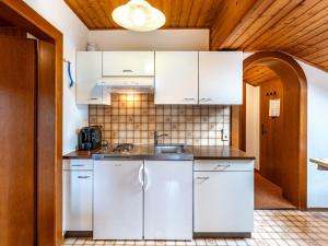 una cocina con armarios blancos y fregadero en Apartment Alpenrose-3 by Interhome, 