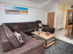 een woonkamer met een bruine bank en een tafel bij Holiday Home Storchennest by Interhome in Norddeich