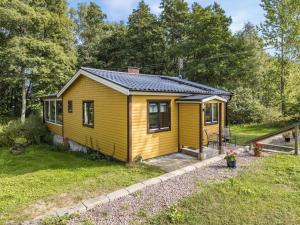 a yellow tiny house in a yard at Holiday Home Kjuge Gula Huset - SKO039 in Fjälkinge