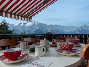 einen Tisch mit roten und weißen Tassen und Untertassen darauf in der Unterkunft Chalet Bivak by Interhome in Nendaz