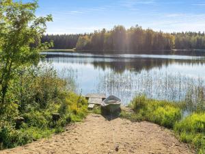 a boat parked next to a bench next to a lake at Holiday Home Jussinlahti by Interhome in Kortteinen