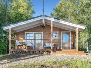 a small log cabin with a porch and chairs at Holiday Home Lahdenpohja by Interhome in Kortteinen