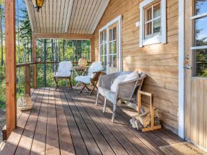 a wooden porch with chairs and a table on it at Holiday Home Lahdenpohja by Interhome in Kortteinen