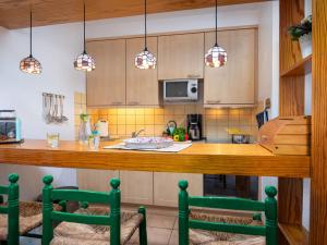 ノルトダイヒにあるHoliday Home Baltrum by Interhomeのキッチン(カウンター、緑の椅子2脚付)