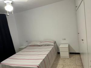 a small bedroom with a bed and a night stand at Apartamento in Almería