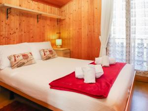 a bedroom with a large white bed with a red blanket at Chalet Le Raccard by Interhome in Saclentse