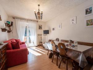 a living room with a table and a red couch at Apartment Ginevra by Interhome in Sauze dʼOulx