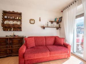 a red couch in a living room with a window at Apartment Ginevra by Interhome in Sauze dʼOulx +25 photos