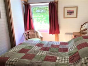 a bedroom with a quilt on a bed and a window at Chalet MacKinnon by Interhome in Ord