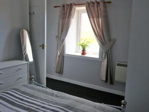 a bedroom with a bed and a window with a potted plant at Holiday Home Flo Anndra by Interhome in Kilmaluag