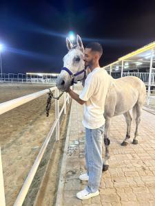 a man holding a horse next to a fence at بيت جرش - Jerash House in Jerash