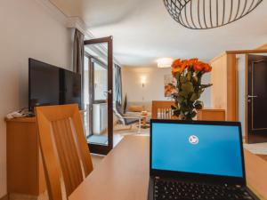 a laptop sitting on a table with a vase of flowers at Apartment Rose by Interhome in Bad Hofgastein