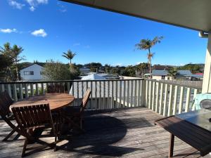 una terraza de madera con mesa y sillas. en Princes Retreat en Ngunguru