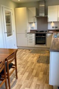 a kitchen with white cabinets and a wooden floor at Holiday Home Devonvale Place by Interhome in Kinross