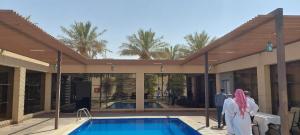 two women standing next to a swimming pool at Antola Resort Al Rimal in Riyadh
