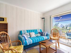 uma sala de estar com um sofá azul e cadeiras em Apartment Le Marbello by Interhome em Le Lavandou