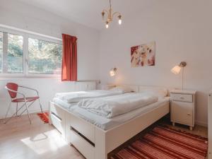 a white bedroom with a bed and a chair at Apartment Schubert-5 by Interhome in Bad Gastein