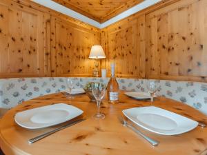 a wooden table with white plates and wine glasses at Apartment Schbert-Franz Top 12 by Interhome in Bad Hofgastein