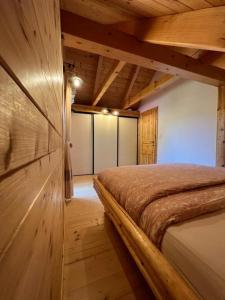 1 dormitorio con 1 cama en una habitación con paredes de madera en Hiška Erika - Wood House Erika, en Šoštanj