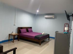 a bedroom with a purple bed in a room at มาดีดี รีสอร์ท in Suphan Buri
