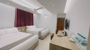 Priyo Nibash Stylish Residential Hotel في داكا: غرفه فندقيه سريرين وتلفزيون