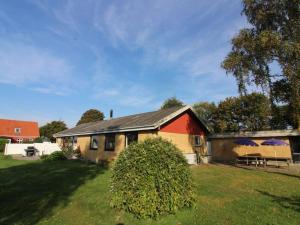 une maison avec un toit rouge et une cour verdoyante dans l'établissement Holiday Home Kolle - 3-2km from the sea in Bornholm by Interhome, à Vester Sømarken