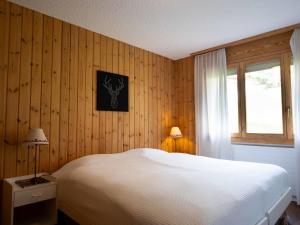 een slaapkamer met een wit bed en een raam bij Apartment Hyacinthe by Interhome in Villars-sur-Ollon